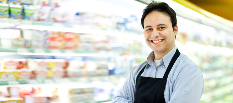 Waikiki IGA Employee standing in front of fridge